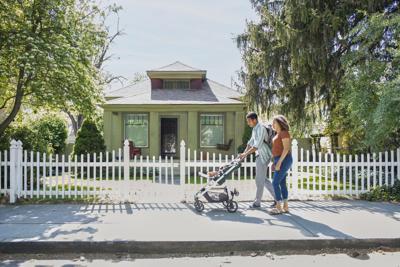 Family walking with stroller, house in background