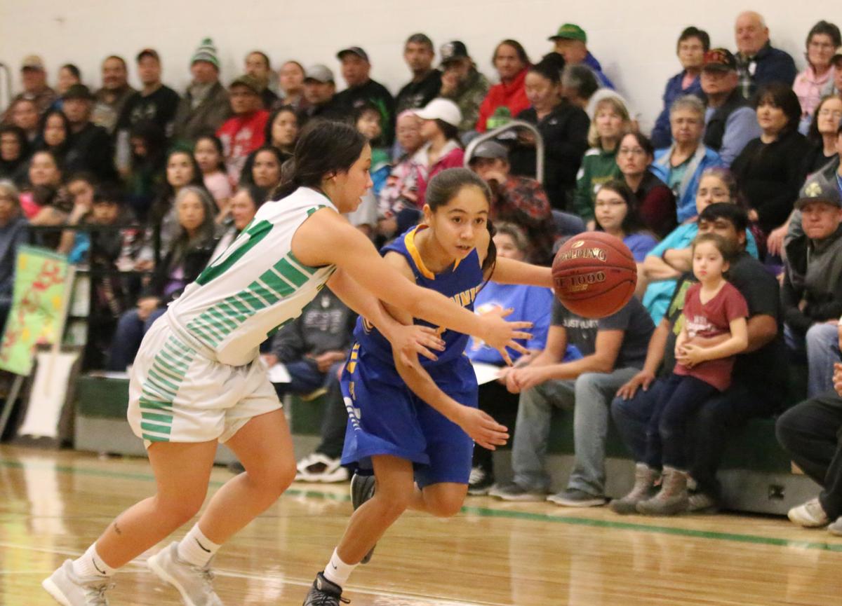 Colville tribal member Ashlynn Hill (No. 4 blue) of Wellpinit drives to the hoop against Randi Finley (Colville tribal member) of Inchelium on Wednesday, Feb 7 in first round of the Northeast District 7 1B girls basketball tournament.