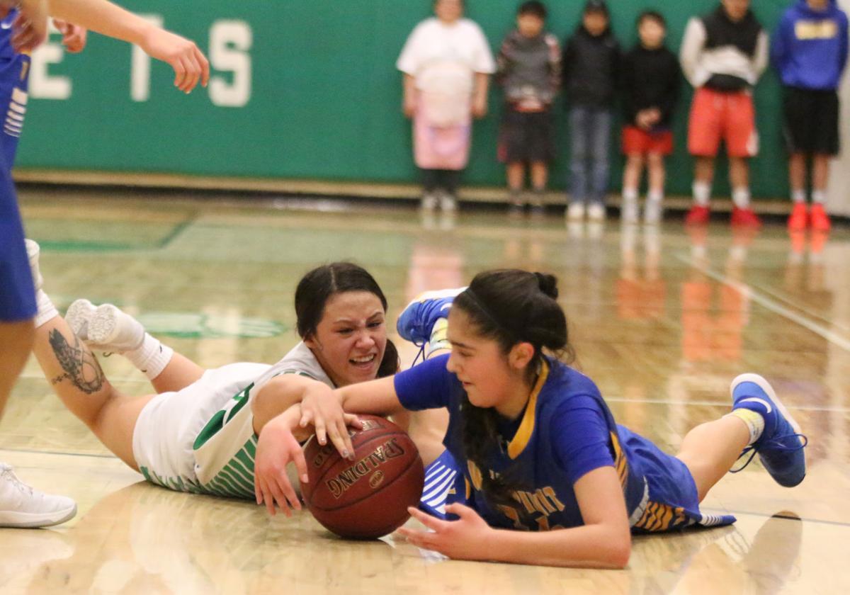 Colville tribal member Randi Finley (No. 20 white) of Inchelium fights for a loose ball against fellow tribal member Lachelle Boyd (No. 14 blue) of Wellpinit on Wednesday, Feb 7 in first round of the Northeast District 7 1B girls basketball tournament. Inchelium defeated Wellpinit 61-58.