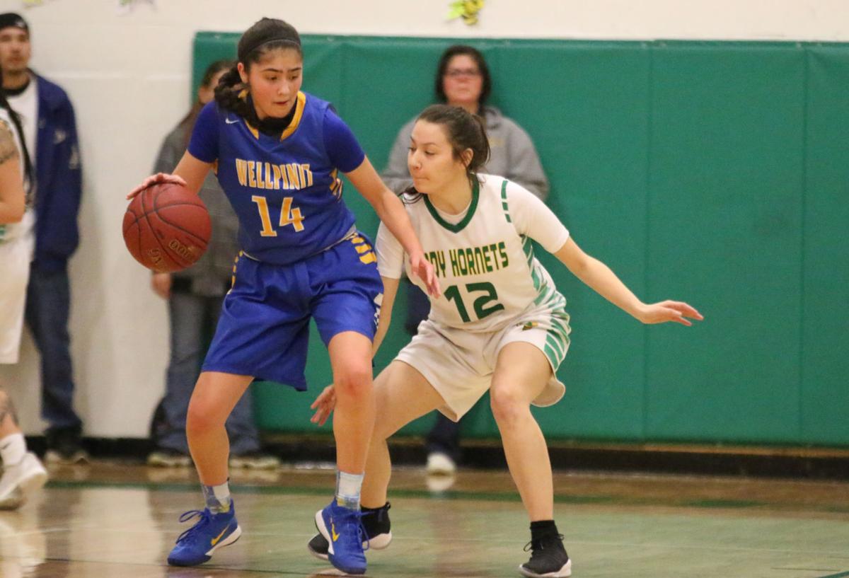 Colville tribal member Lachelle Boyd (No. 14 blue) of Wellpinit protects the ball from fellow tribal member Cloey Simpson (No. 12 white) of Inchelium on Wednesday, Feb 7 in first round of the Northeast District 7 1B girls basketball tournament. Inchelium defeated Wellpinit 61-58.