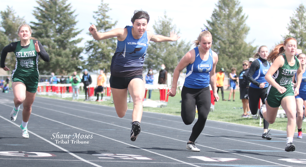 Colville tribal member Mackenzie Arden (blue) of Wilbur-Creston crosses the finish line in first place in the championship race of the 100-meter dash at the District 7 and 9 Track and Field Championships (May 7) at Ritzville High School