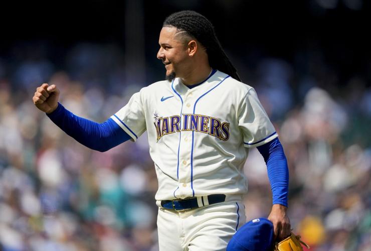 Seattle Mariners' Teoscar Hernandez holds a trident in the dugout as  teammates throw seeds at him to celebrate his solo home run against the  Kansas City Royals during the second inning of