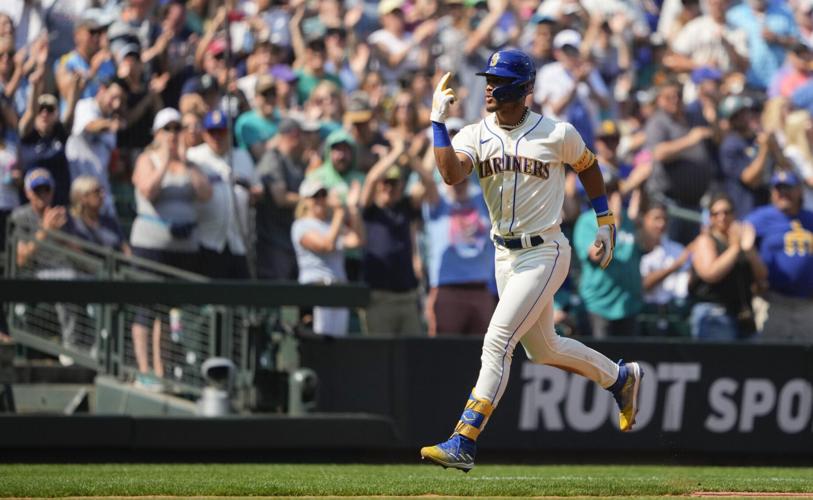 Seattle Mariners' Teoscar Hernandez holds a trident in the dugout as  teammates throw seeds at him to celebrate his solo home run against the  Kansas City Royals during the second inning of