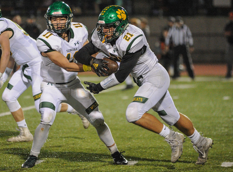 Sonora High's (11) Nick Crockett hands the ball off to Sonora High's (21) Elijah Macdonald during the high school game between the Sonora High School Wildcats and Summerville High School Bears at Summervilles Thorsted Field on November 1, 2019 in Tuolumne, CA.