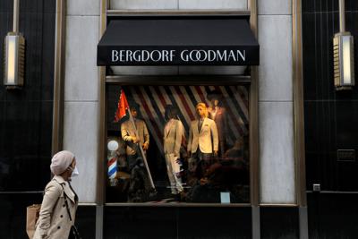 FILE PHOTO: A person wearing a face mask walks by Bergdorf Goodman on Fifth Avenue as retailers reported a downturn in sales related to the coronavirus outbreak in Manhattan, New York City