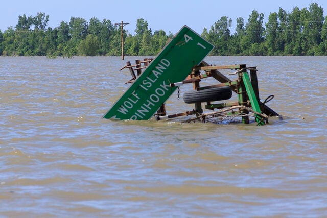 Roadsign taken by floodwaters is entangled on submerged farm equiptment