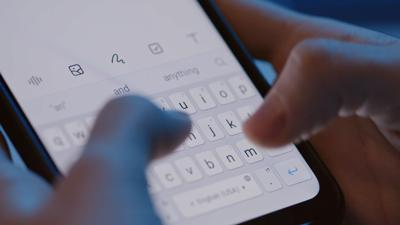 close-up-of-unrecognizable-person-holding-smartphone-in-hands-typing-message-on-keyboa-SBI-349487594.jpg