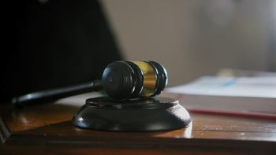 judges-hand-with-wooden-judge-gavel-and-american-flag-background-close-up-shot-SBI-351244719.jpg