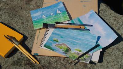 artist-working-place-with-finished-watercolor-pictures-and-art-supplies-painting-seasc-SBI-351258824.jpg