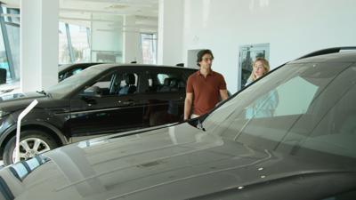 Young couple inside car dealership