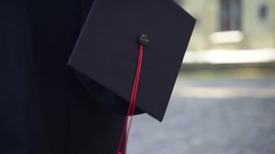 Student walking with cap in hand