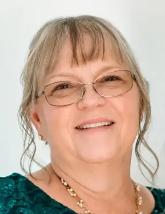 Woman wearing glasses, necklace and t tone green top