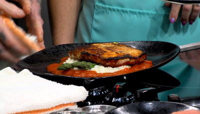 swordfish dish plated on black plate, aqua color apron in background