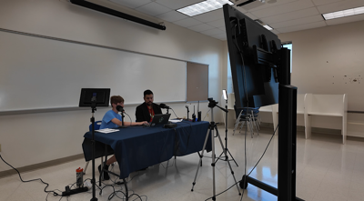 RJ Larimer, an 8th grader at North Dorchester Middle School, and Assistant Principal Mark Pages record the school's morning announcements from the school's newly upgraded TV studio.