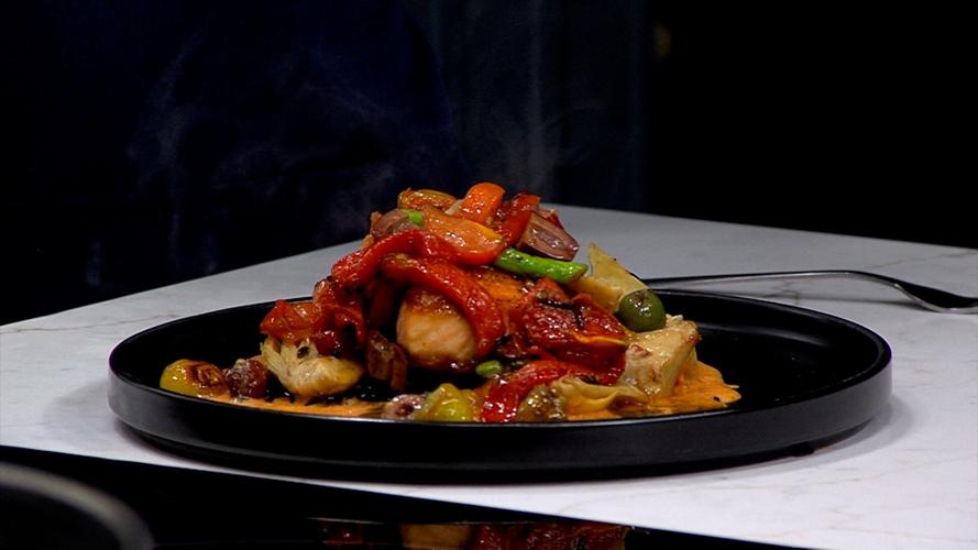 Salmon dish, topped with peppers plated on black plate on with counter