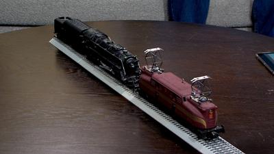Train cars sitting on a piece of train track. set up on a wooden table