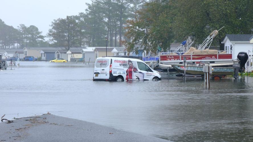 A white work van parked on a flooded street. Water close to the top of the wheels.