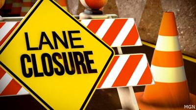 Construction sign with lane closure written on it, next to an orange traffic cone.