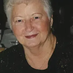 Woman with Short white hair, wearing black top with dark background