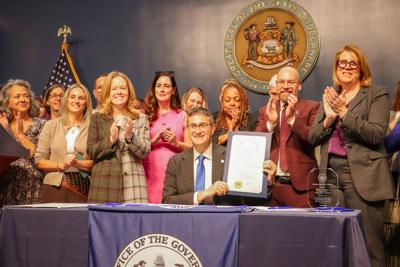 Gov. Meyer holding up a signed proclamation designating October as Domestic Violence Awareness Month in the First State.