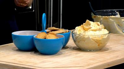Pumpkin dip served in a clear bowl, graham crackers and vanilla wafers in blue serving dish sitting on a large cutting board
