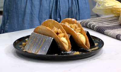 desert tacos sitting in a taco tray, plated on a black plate
