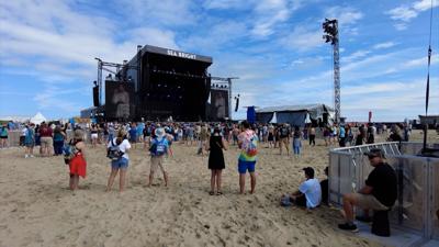 The "SEA BRIGHT" stage surrounded by a crowd with a performer at the Ocean's Calling Music Festival from a previous year. 