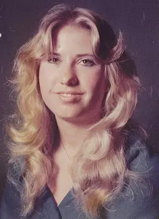 woman with long wavy hair wearing a gray top with gray color background