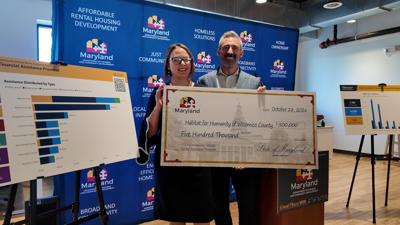 Maryland Department of Housing and Community Development Secretary Jake Day and Habitat for Humanity of Wicomico County CEO stand side-by-side holding a check from the state for $500,000 to keep Marylanders housed. 