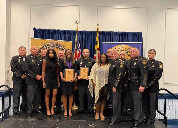 Members of the Wicomico County Sheriff's Office, members of Corporal Hilliard's family, and Corporal Kevin Perretta stand on stage with their honors. 