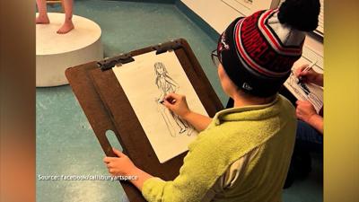Woman drawing.  She is in a sitting position wearing a lime green long sleeve shirt and a White red and black Bennie on her head.