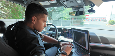 Dover police officer in patrol car looking at computer.