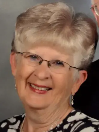 Woman with blond/gray hair, wearing glasses and earrings, black and white top