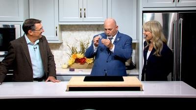 Man, bald, wearing a blue suit, holding coins, standing between Steve and Lisa