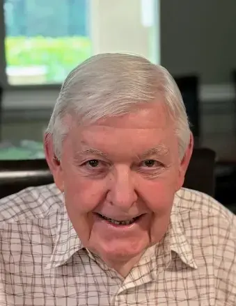 Man with white hair wearing a white, and brown checkered shirt