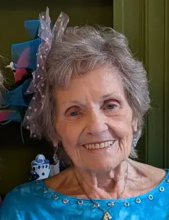 Woman with Salt and pepper hair wearing a blue dress and necklace