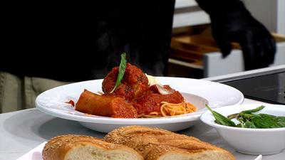 plated on a white plate is spaghetti and link sausage and a small white plate of  bread