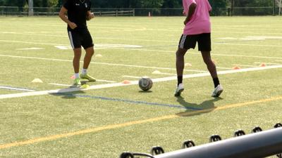 Two teens practicing soccer on a Kent County field.
