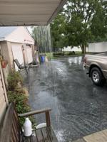 Rain pours off an overhang into a flooded driveway in Milford.