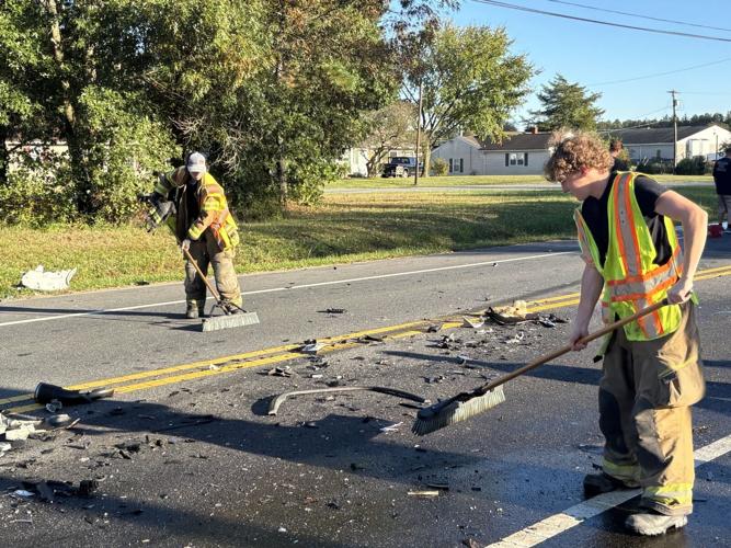 Two people in safety vests sweeping trash off the road after a crash in Delmar, 10/20.