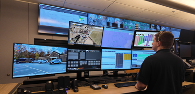 911 emergency dispatcher standing in front of screens waiting for call to come in.