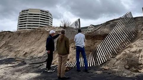 Ocean City employees stand on the sand with their backs to the camera while observing damaged dune fencing after a nor'easter slammed Delmarva last weekend.