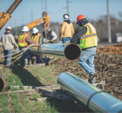 A gas company crew installs natural gas pipelines using heavy machinery. 