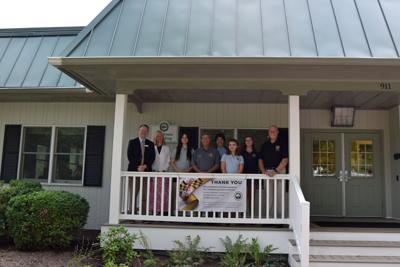 A group of school leaders, delegates, and students pose under the building's new roof. 