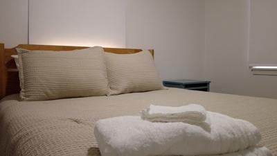 Bed freshly made with towel and wash cloth sitting at the edge of the bed. 