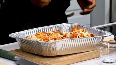 Tortellini Dish, plated in a large aluminum pan sitting on a large cutting board .  