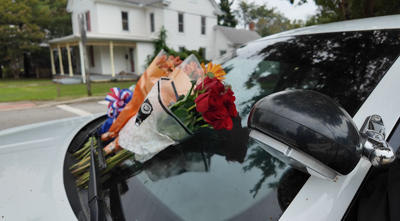 Flowers lay on a Denton police patrol car as the community mourns the death of longtime Police Chief George Bacorn.