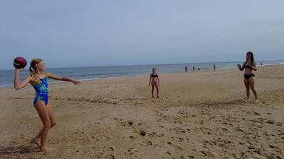 Three girls playing with a football on Dewey Beach, DE