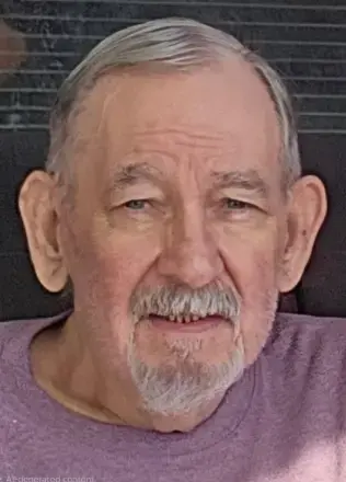 man with Short salt & pepper hair, mustache, and goatee. wearing a purple t-shirt 