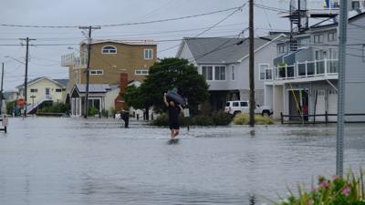 A man carrying a suitcase wades through flooded streets in Dewey Beach.